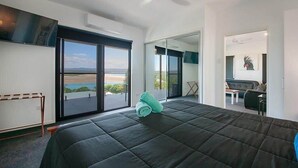 Une chambre d’hôtel moderne dotée d’un grand lit, d’un ventilateur de plafond, d’une vue sur l’extérieur grâce à une porte coulissante et d’un balcon.