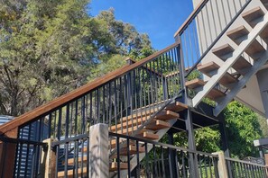 A staircase with a wooden handrail and metal balusters, leading to a building with a beige exterior. - Sunset Beach House 1770 Level 3 (Seventeen Seventy)