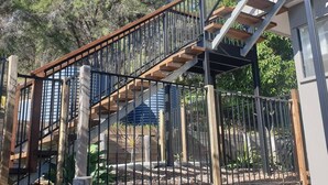 Un escalier en métal avec des marches en bois menant à un bâtiment.