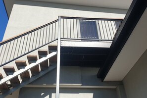 Un escalier moderne avec une rampe en métal menant à un balcon doté d’une fenêtre.
