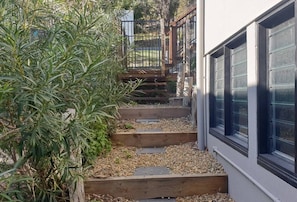 A wooden staircase leading to a door, surrounded by gravel and plants. - Sunset Beach House 1770 Level 3 (Seventeen Seventy)
