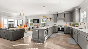 Una cocina moderna con gabinetes grises, una isla central y un área de comedor con sofá gris.