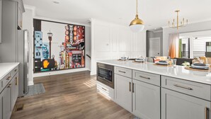 Una cocina moderna con armarios blancos, horno integrado y una isla grande con microondas.