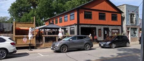 A two-story building with a red facade and a stone base, featuring a restaurant with outdoor seating and a sign that reads "Casa Hugo."