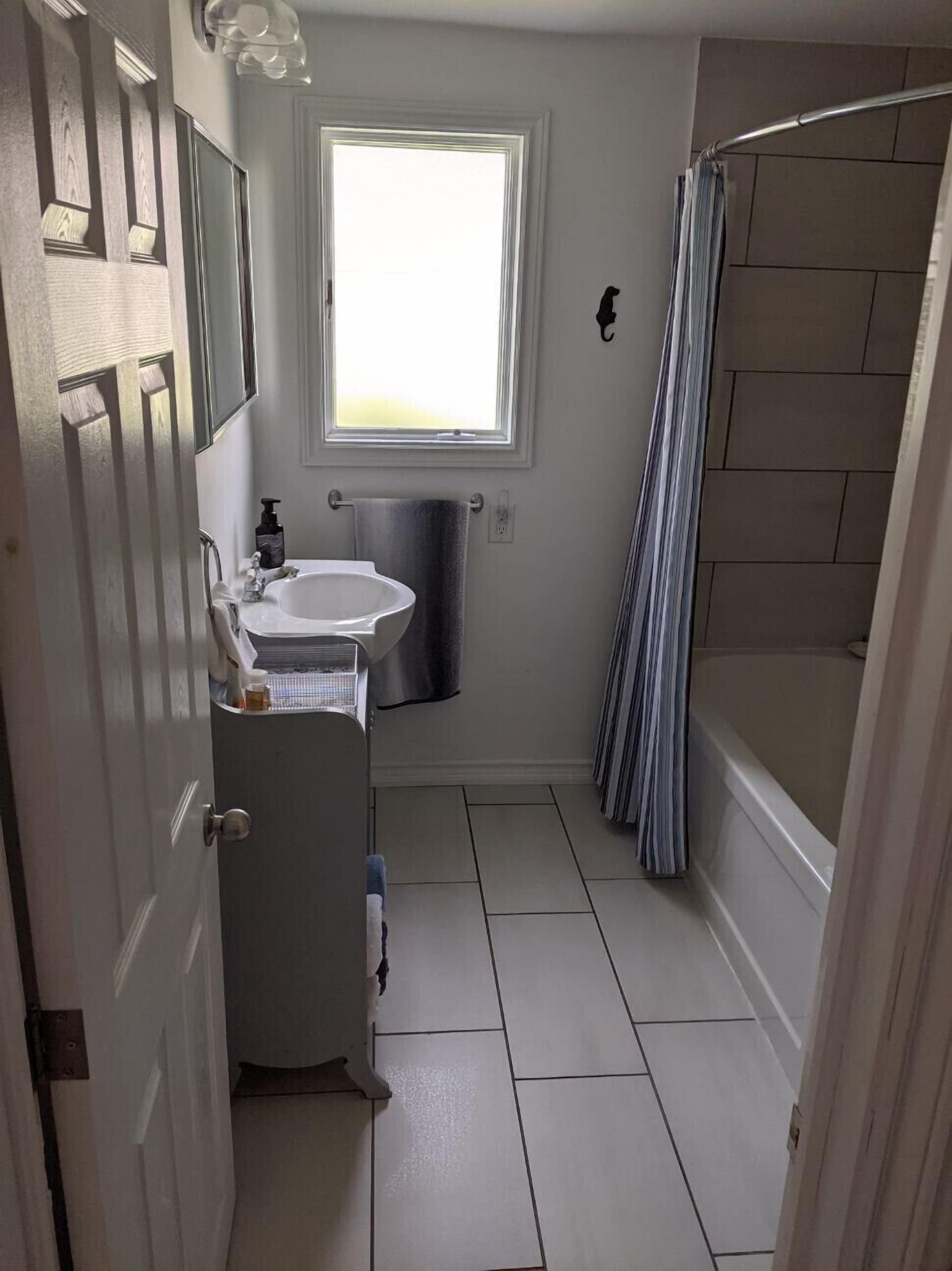 A compact bathroom with a window, a sink, a toilet, and a shower area.
