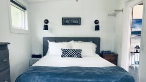 Un dormitorio con cama, cómoda, mesita de noche y un letrero en la pared que dice "LAKE HOUSE".