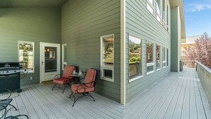 A covered porch with a grill, two chairs, and a table.