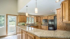 A kitchen with wooden cabinets, granite countertops, and stainless steel appliances.