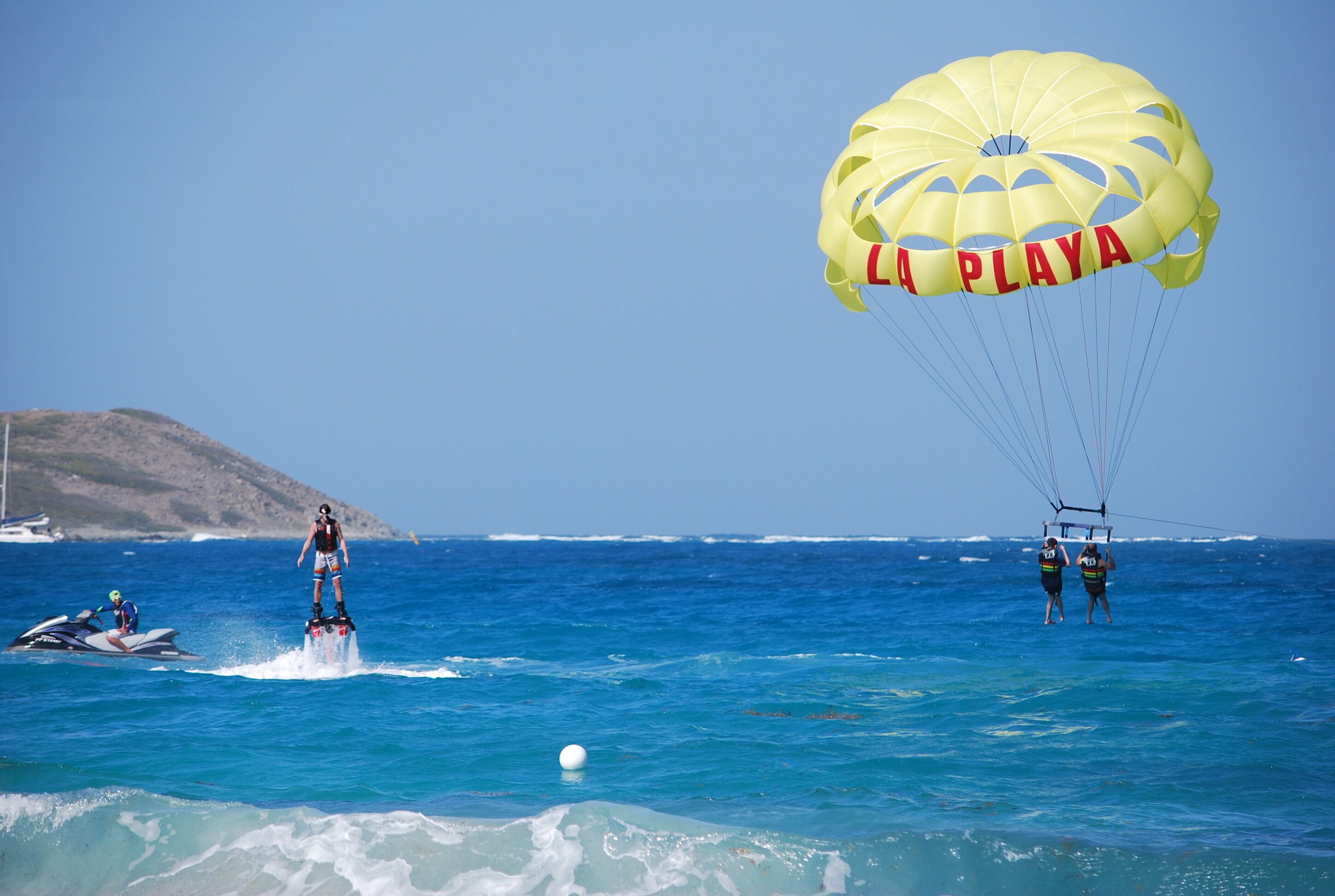 Une activité de parachute ascensionnel par beau temps, avec un paysage montagneux en toile de fond.