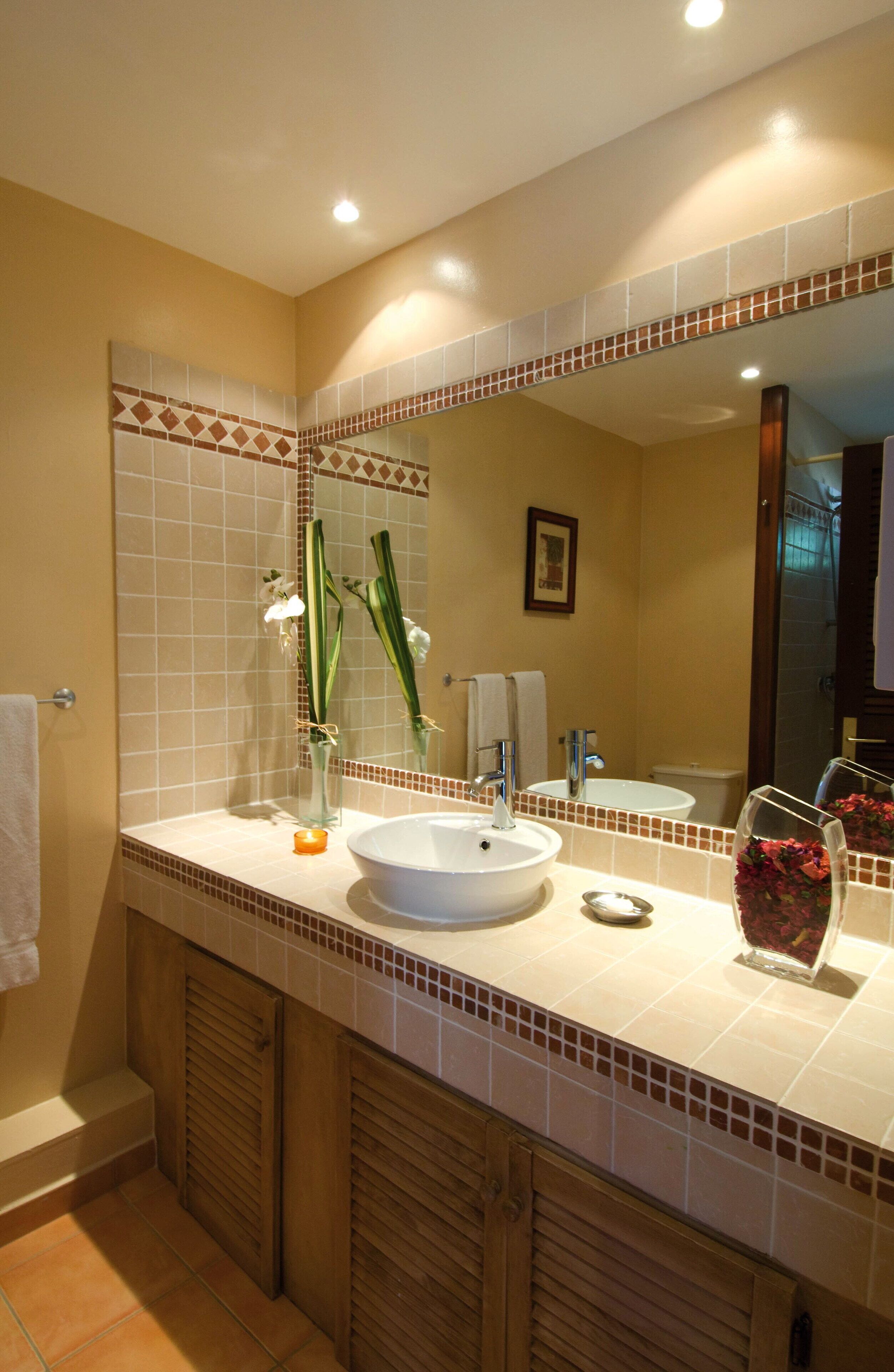 A bathroom with a large mirror, a sink, and a toilet.
