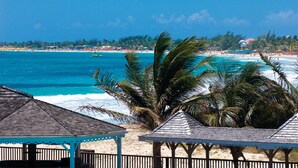 Una playa con aguas turquesas cristalinas, palmeras y cabañas de playa.