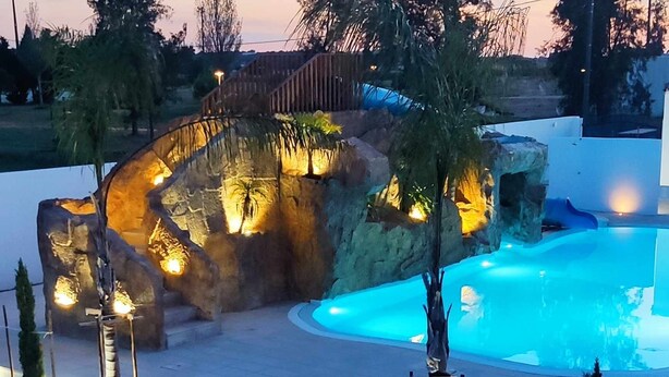 A swimming pool with a rock formation and steps leading to it. - Casa Almeida - Apt. T0 (Vimieiro)