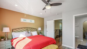 A bedroom with a bed, bedside lamps, a ceiling fan, and a door leading to another room. - 3bed/3ba home- huge backyard - Mins from Downtown (Houston)