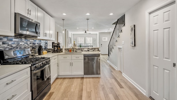 A modern kitchen with white cabinets, stainless steel appliances, and a tiled backsplash. - 3bed/3ba home- huge backyard - Mins from Downtown (Houston)