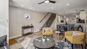 A modern living room with a ceiling fan, a staircase, and a kitchen area. - 3bed/3ba home- huge backyard - Mins from Downtown (Houston)