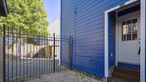 A blue house with a white door, a gravel driveway, and a metal fence. - 3bed/3ba home- huge backyard - Mins from Downtown (Houston)
