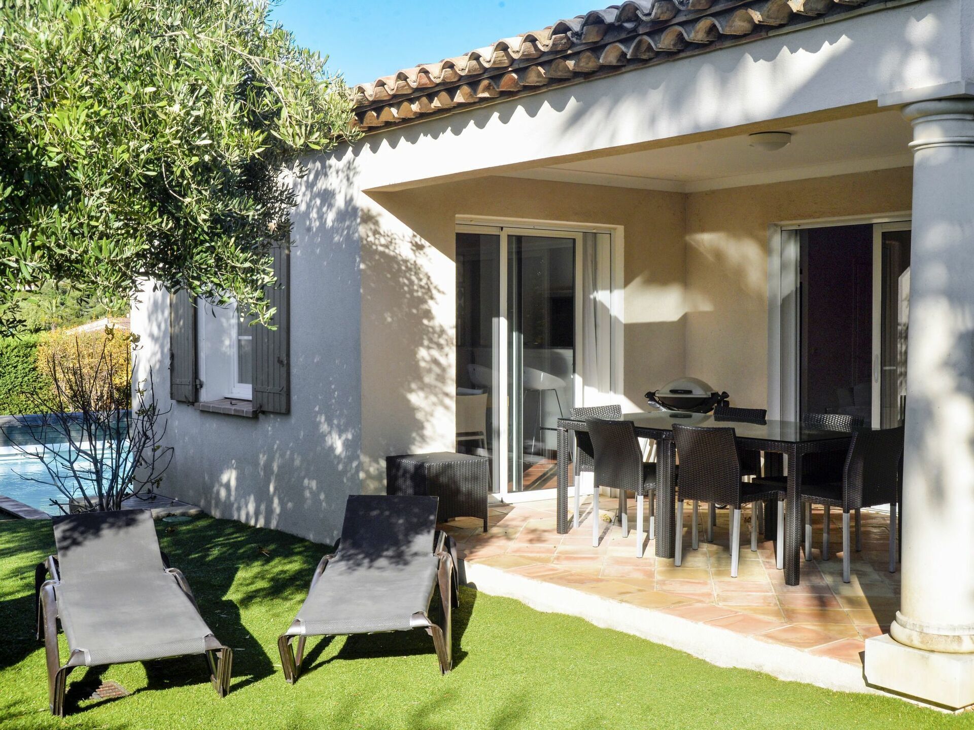 Un patio con mesa y sillas, piscina y dos sillones.