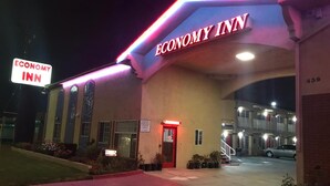 A building with a sign reading "Economy Inn" and a parking lot in front.