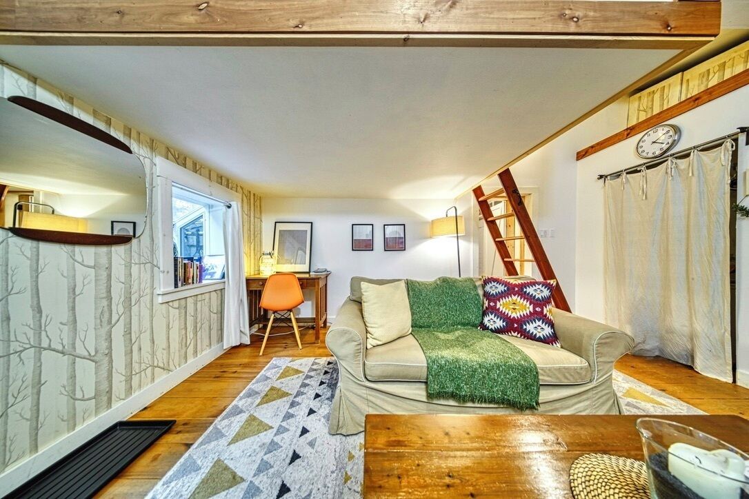 Een gezellige woonkamer met een bank, een houten salontafel en een ladder tegen de muur.