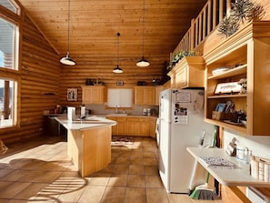 A kitchen with wooden cabinets, a central island, a refrigerator, and a sink.