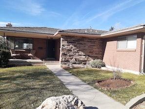 A residential house with a stone facade, a front porch with seating, and a clear sky. - Adventure Basecamp - Ski, Hike & Explore SLC (Salt Lake City)