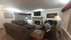 A living room with a fireplace, a television mounted on the wall, and a sofa.
