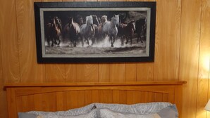 A wooden-paneled room with a bed featuring a patterned bedspread and multiple pillows.