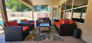An outdoor patio with wicker furniture, a pool, and a view of the backyard. - Large oasis, pool heater, spa, putting green (Avondale)