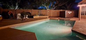 A swimming pool with a brick wall and a wooden deck area.