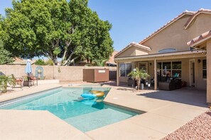 A swimming pool with lounge chairs and a covered patio area.