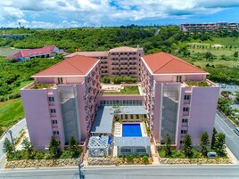 Un hotel de varios pisos con un patio central, una piscina y vistas del paisaje circundante.