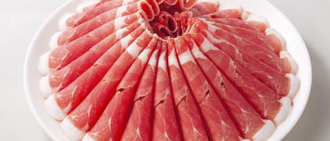 Une assiette de fines tranches de charcuterie disposées en éventail sur une assiette blanche.