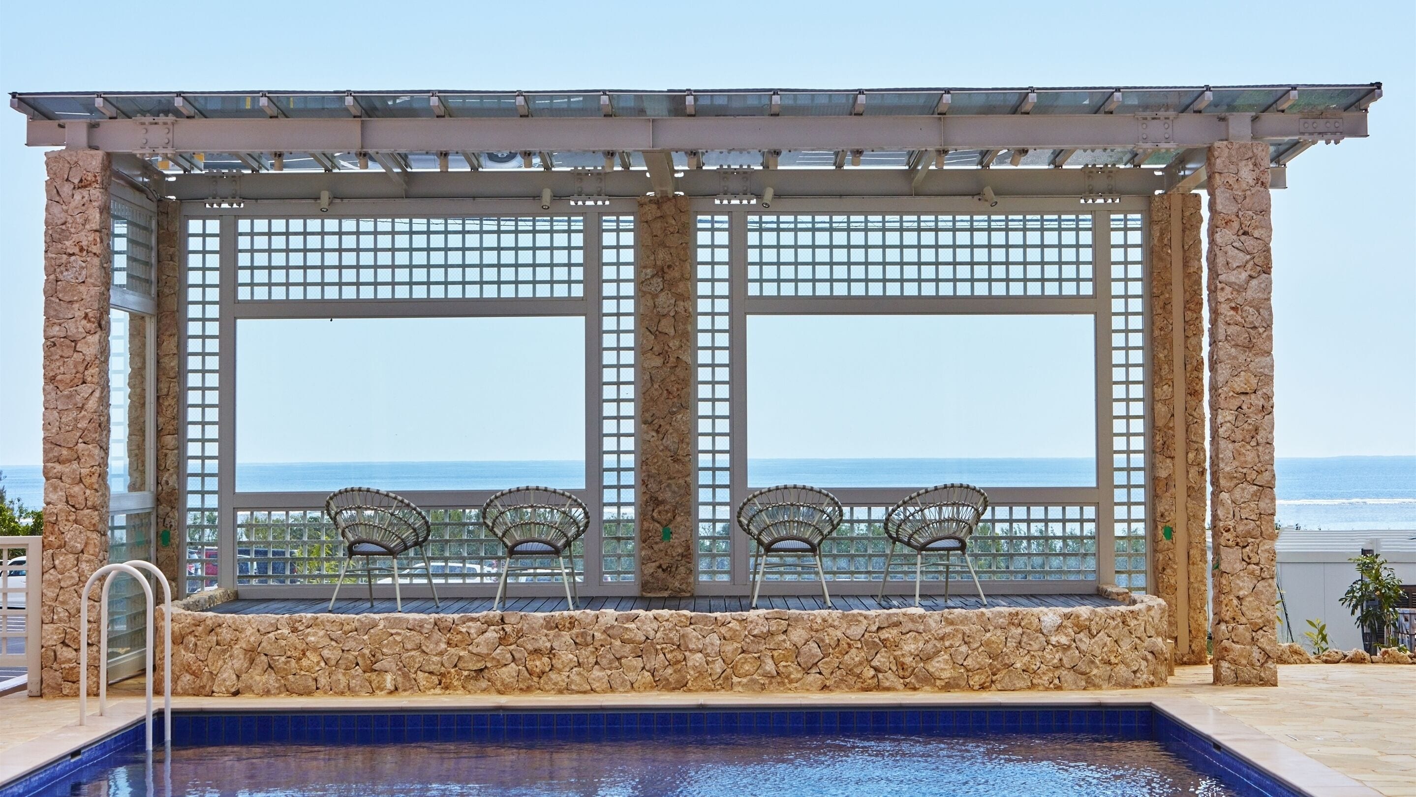 Area piscina con pareti in pietra e vista sull'oceano.