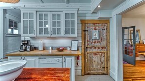 A kitchen with white cabinets, a wooden countertop, and a rustic door. - Family Winter House in the ❤️ of the Eastern Townships (Ayer's Cliff)