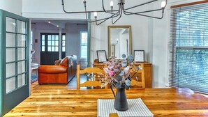 A dining area with a wooden table, a vase with flowers, and a chandelier. - Family Winter House in the ❤️ of the Eastern Townships (Ayer's Cliff)