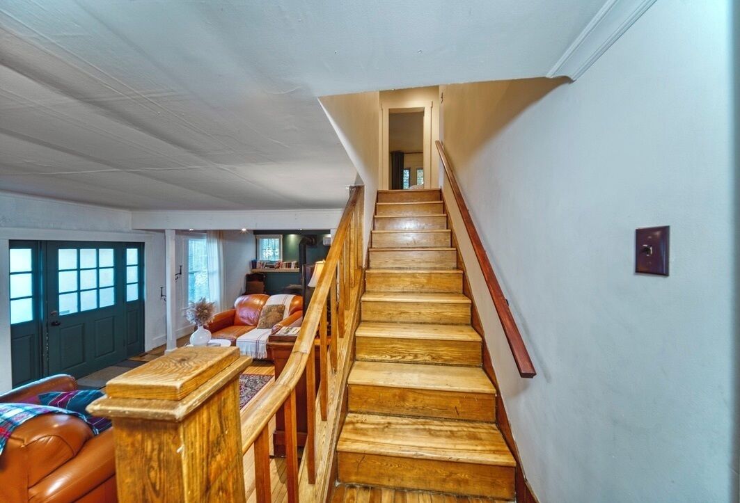 A staircase with wooden steps and a wooden handrail leading to an upper floor.