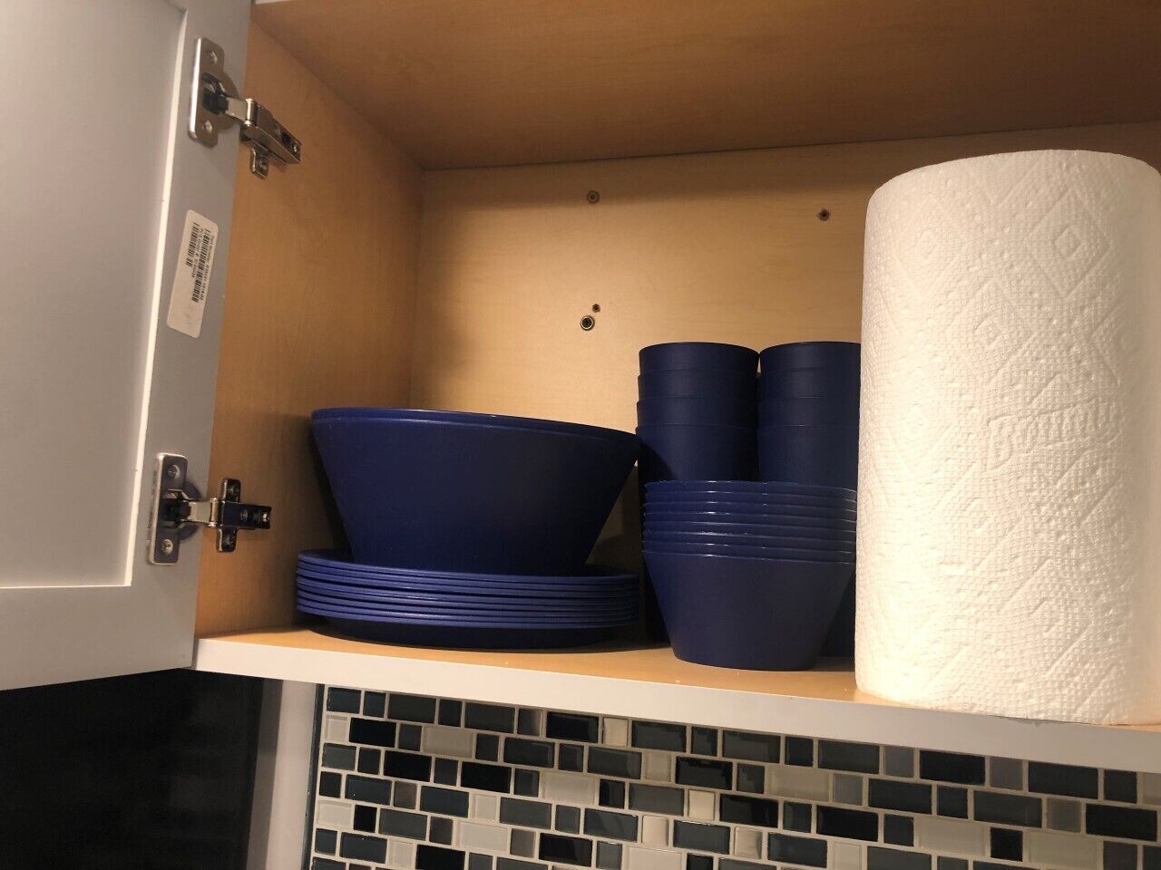 Ein Küchenschrank mit blauem Geschirr und einer Küchenpapierrolle.
