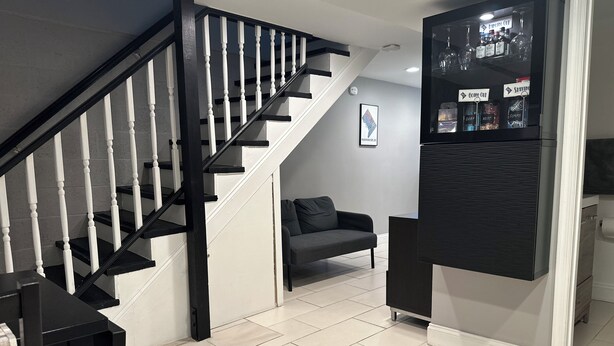 Ein modernes Interieur mit Treppe, einer Couch und einem an der Wand befestigten Schrank mit Spirituosenflaschen.