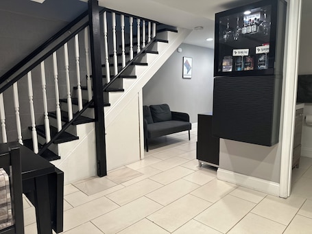 A modern interior with a staircase, a sofa, and a wall-mounted cabinet with liquor bottles.