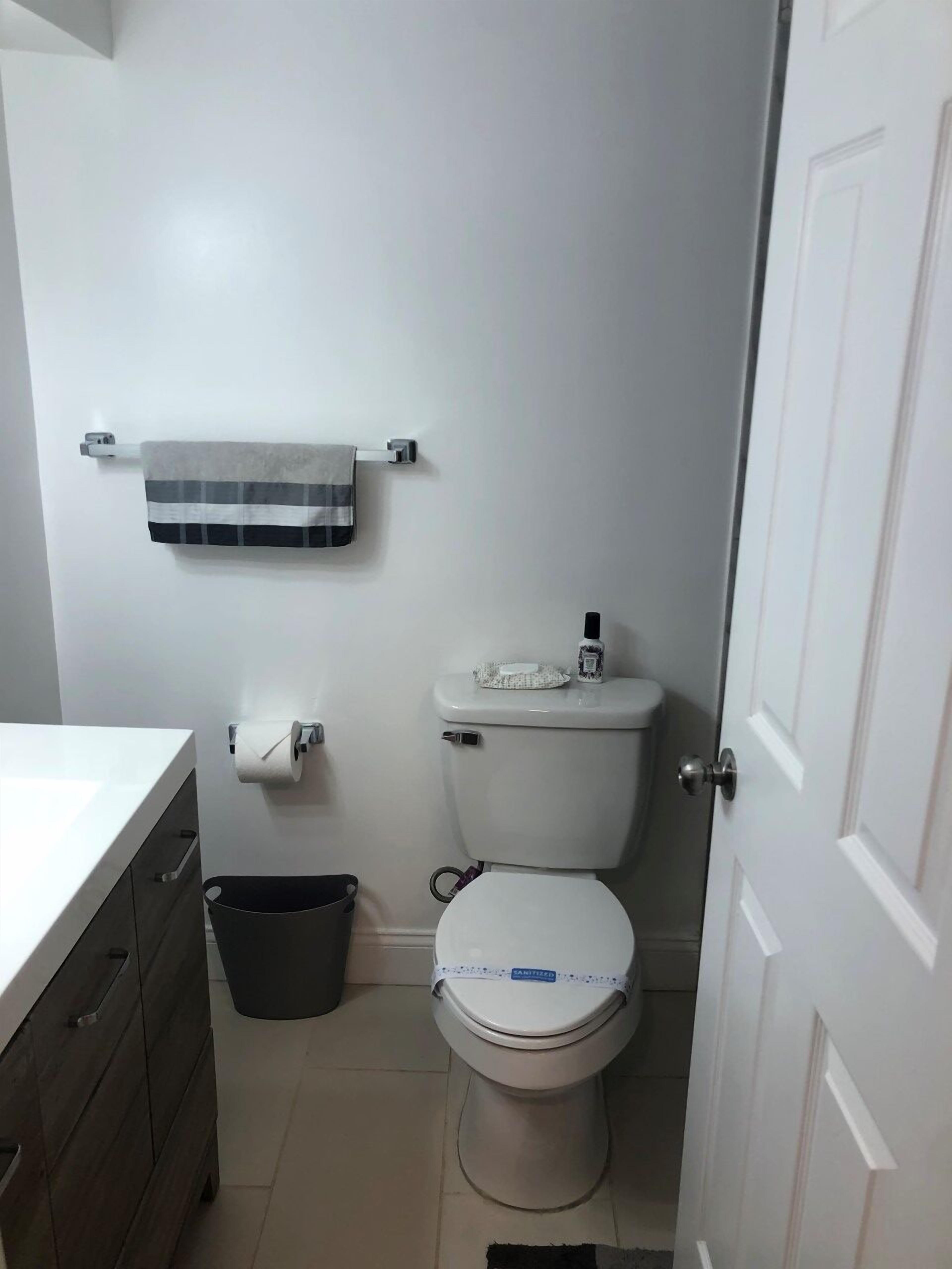 Ein kleines Badezimmer mit Toilette, Handtuchhalter, Papierkorb und Toilettenpapierhalter.