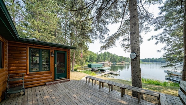 Una cabaña de madera con un muelle, una banca y un embarcadero que se adentra en un lago.