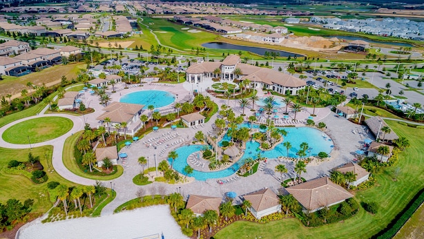 Vue aérienne d’un complexe hôtelier doté de plusieurs piscines, d’un parcours de golf et d’immeubles résidentiels.