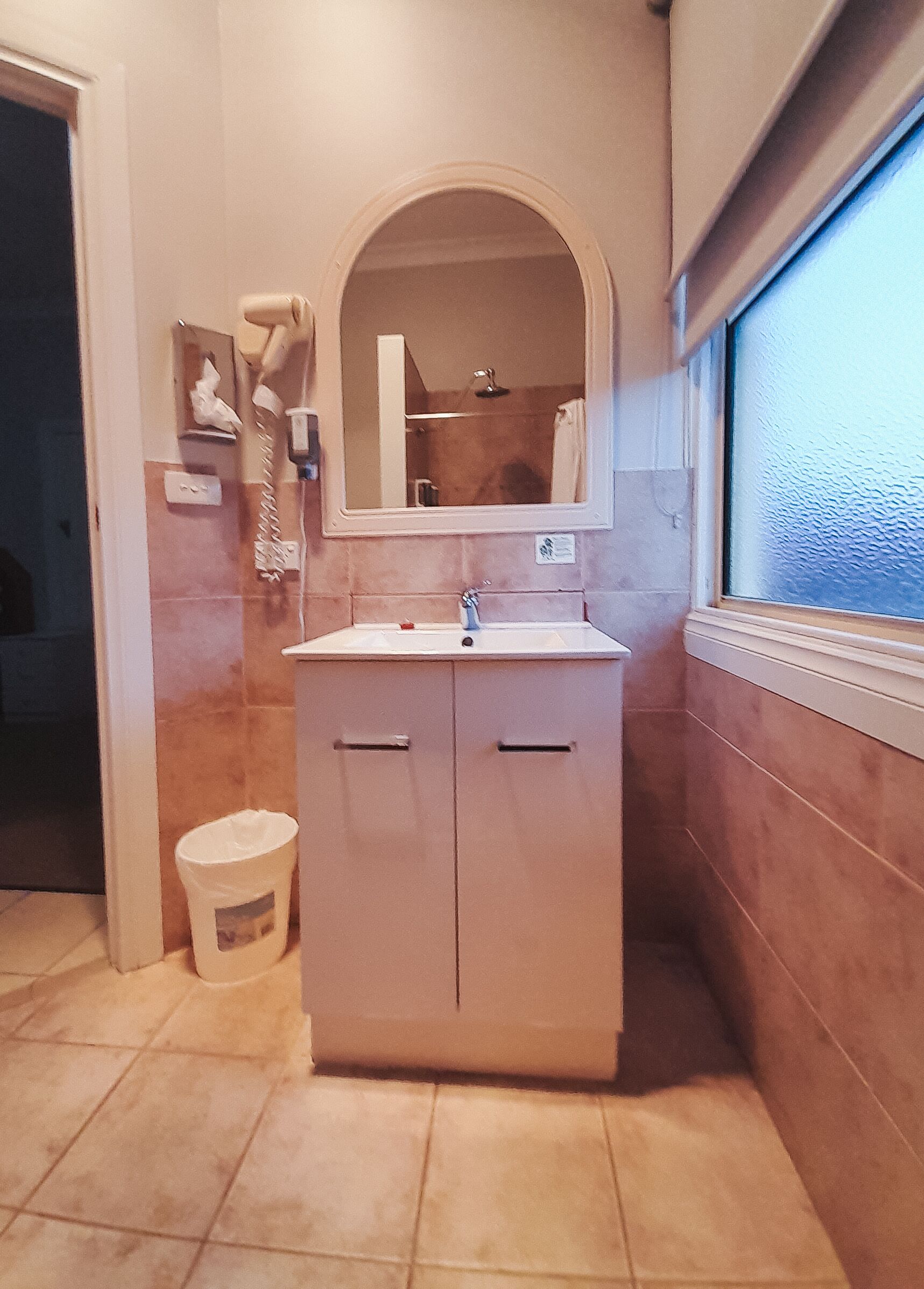 A bathroom with a sink, mirror, and a window.
