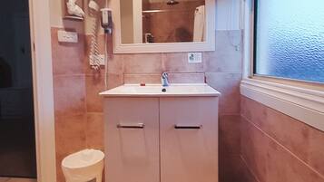 A bathroom with a sink, mirror, and a window.