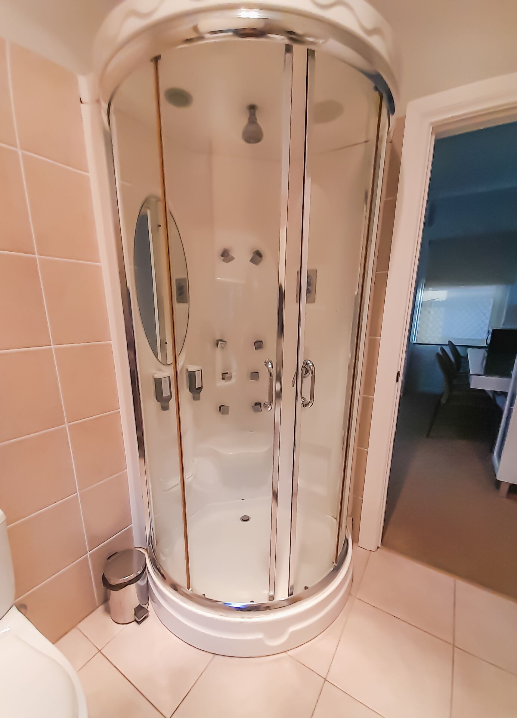 Un bagno moderno con cabina doccia in vetro, un water e un cestino.