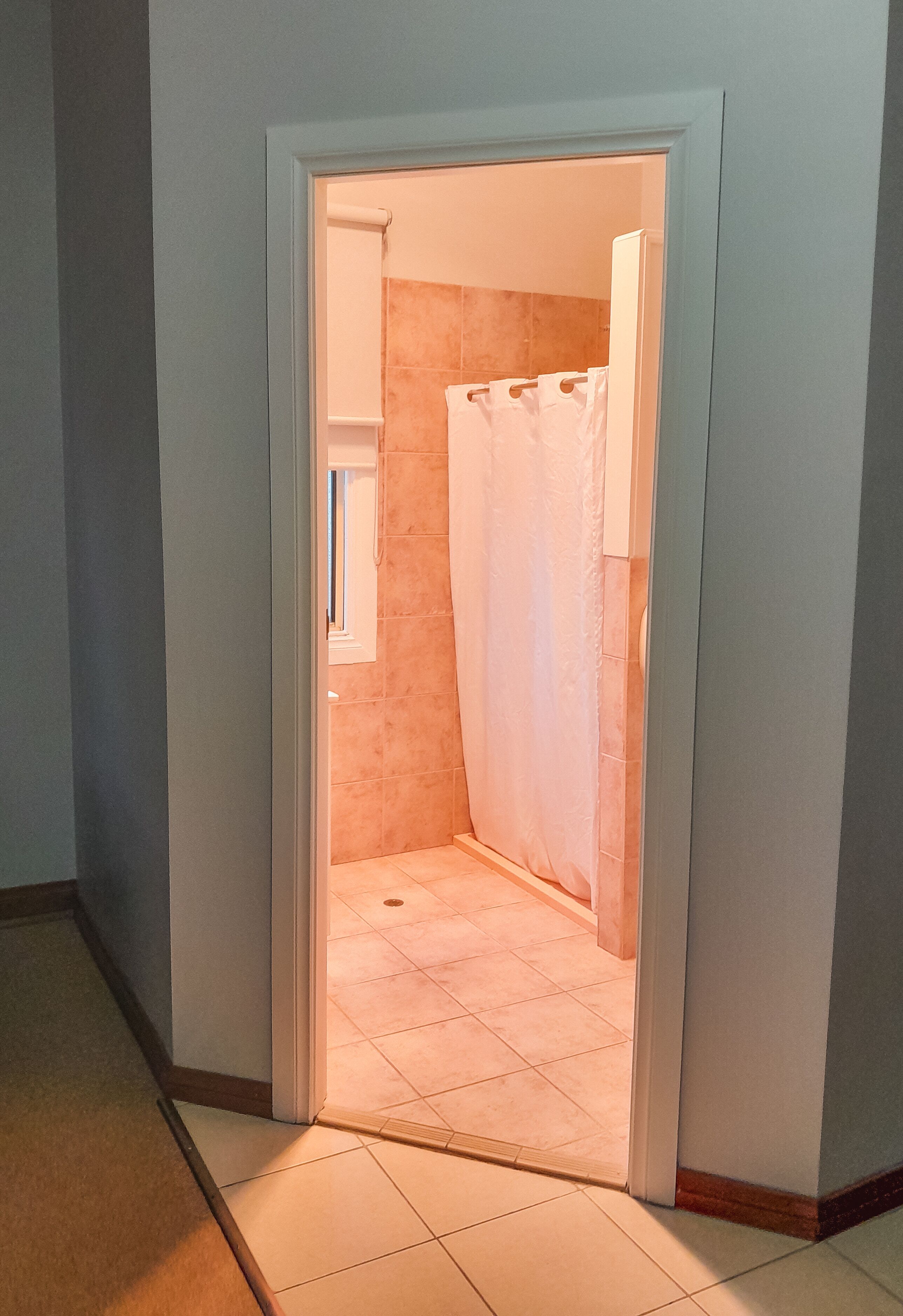 Un pasillo estrecho que conduce a un baño con cortina de ducha.