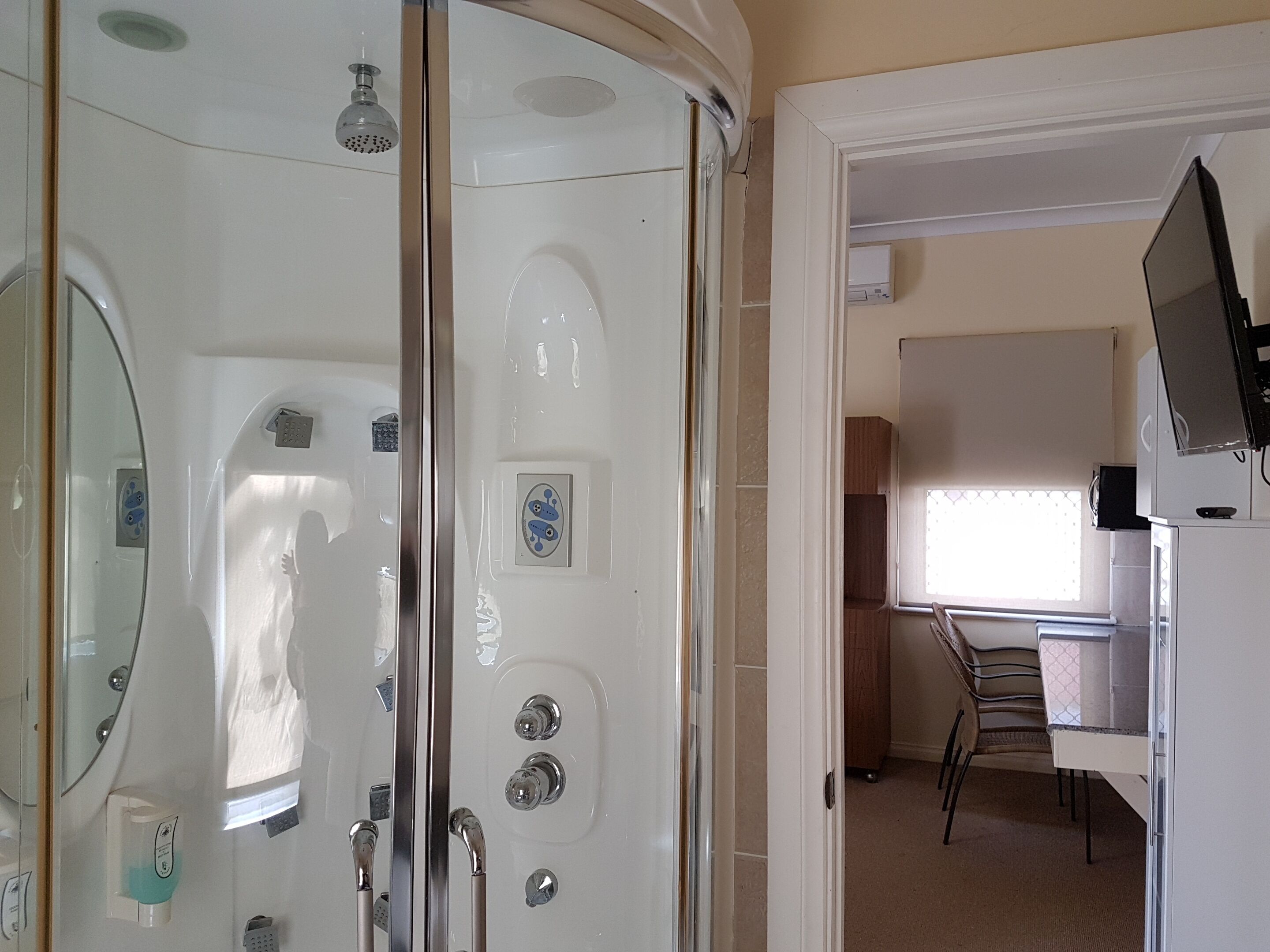 A bathroom with a glass shower enclosure, a toilet, and a sink.
