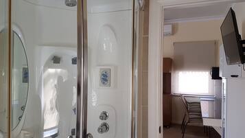 A bathroom with a glass shower enclosure, a toilet, and a sink.