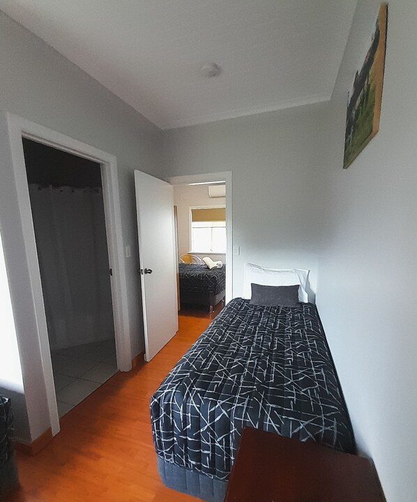 Un dormitorio con cama, una puerta y vista a otra habitación.