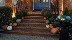 A brick building with a blue door, steps leading up to the entrance, and decorative pumpkins and shrubs. - Great Get Away Home  (Henrico)